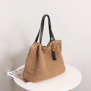 Large vintage woven straw tote bag with black leather handles and tassel for beach travel