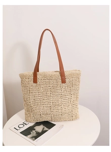 Close-up of woven straw texture and premium brown leather handles on a summer tote bag
