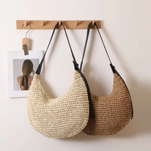Detail of hand-woven straw hobo bags with leather straps hanging on a wooden wall hook