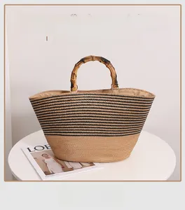 Detail of hand-woven straw tote with natural bamboo handles and chic black stripes