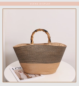 Bamboo handle detail on striped straw tote bag placed on white table in scene display