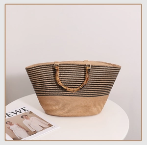 Detail of large striped straw tote bag featuring vintage-style bamboo handles on a white table