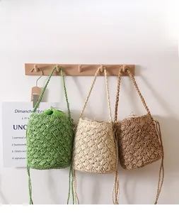 Detailed view of woven straw bucket bags with drawstring closures in three natural colors