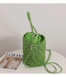 Macro shot of green straw bucket bag showing woven texture and satin drawstring lining
