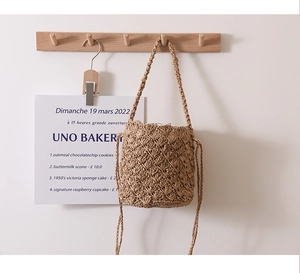 Detail of hand-woven straw bucket bag with intricate shell pattern texture and drawstring