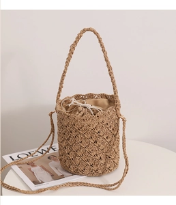 Detail of hand-woven straw bucket bag showing drawstring lining and crossbody strap