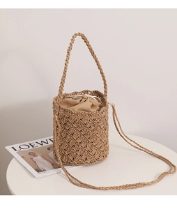 Detailed macro shot of the hollow-out straw bucket bag with a beige drawstring lining