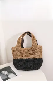 Detail of a two-tone woven straw tote bag with black and khaki contrast on white background