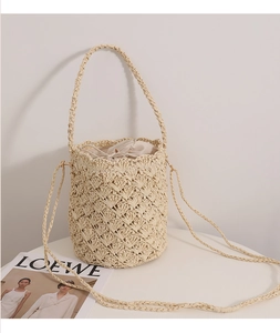 Detail of handwoven straw bucket bag featuring drawstring liner and intricate hollow pattern