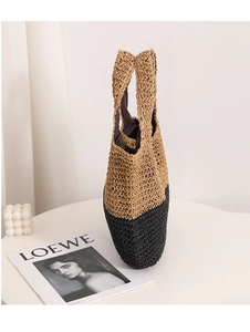 Detailed close-up of the two-tone straw bag featuring a natural and black woven contrast