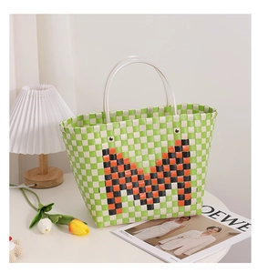 Close-up of green and white checkered woven tote bag featuring a large M letter and clear handle