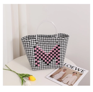 Detail of black and white woven tote bag featuring a pink M letter and transparent handles