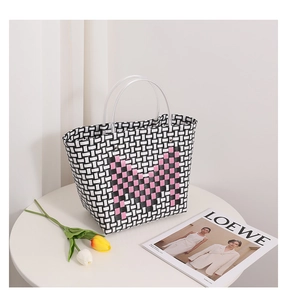 Detail of woven tote bag with contrast patterns and transparent round handles