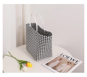 Detail view of a black and white checkered woven tote bag with white tubular handles