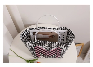 Detail of hand-woven bucket bag with pink heart pattern and clear round handles