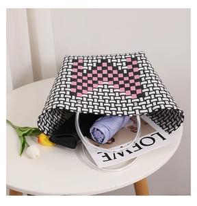Detail of hand-woven tote bag with pink heart pattern and clear resin handles
