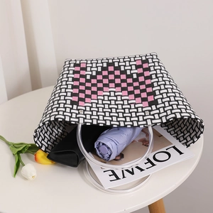 Handwoven striped tote bag with pink heart and clear round handles on a white table