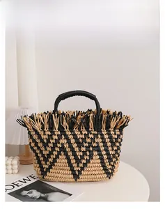 Detailed close-up of straw woven tote with black fringe trim and faux leather handles