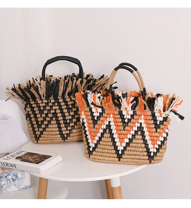 Detail of bohemian straw totes with long raffia fringe and leather handles for summer
