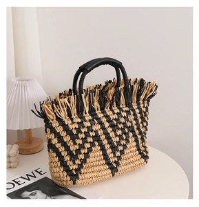 Detail of bohemian straw tote bag featuring geometric weave and decorative fringe edges