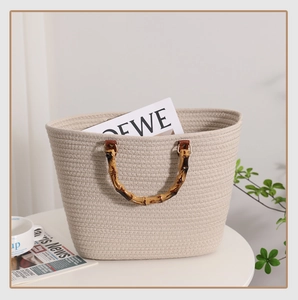 Detail der handgewebten Baumwoll-Tasche mit Vintage-Bambusgriffen auf einem weißen Tisch