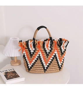 Detail of multi-colored straw tote bag with fringe texture on a minimalist French table