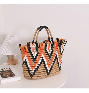 Detail of bohemian woven straw tote featuring colorful geometric patterns and fringe trim