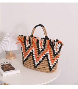 Detail of hand-woven straw tote with colorful geometric patterns and fringe edges