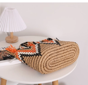 Detailed macro view of the oval woven base and fringe edges of the bicolor straw handbag