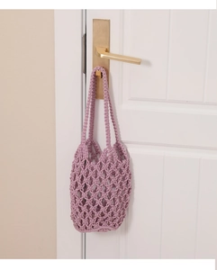 Detalle de un bolso de ganchillo lavanda hecho a mano colgado de un pomo de puerta