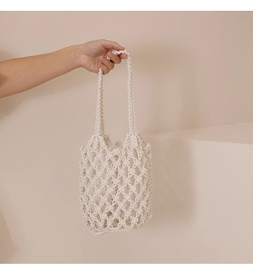 Detalle de bolso de playa en macramé crema con patrones de nudos y asa resistente