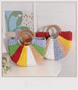 Rainbow woven straw handbag with colorful stripes on white table for summer beach vacations