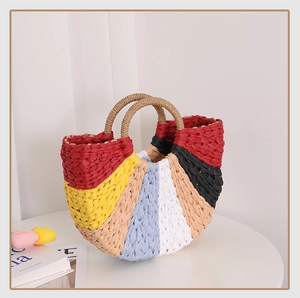 Close-up of semi-circle straw bag with colorful woven patterns and top handles