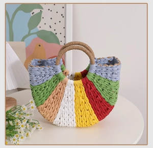 Detail of a handmade semi-circular rainbow straw bag with colorful woven texture and handles