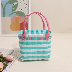 Detail der mintgrün und weiß geflochtenen Strohtasche mit rosa Griffen für den Sommer