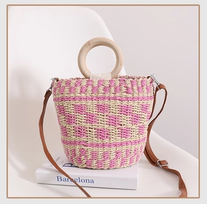 Détail du sac en paille tressé rose et beige avec poignée ronde en bois et bandoulière