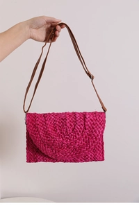 Detail of rose red woven straw bag with textured rope pattern and brown leather strap