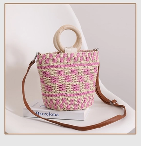 Gros plan d'un sac en paille tressée rose et beige avec poignée en bois ronde