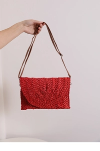 Detail of red corn husk envelope bag with brown strap for summer beach vacation