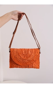 Detail of orange woven corn husk crossbody bag featuring spiral texture and leather strap