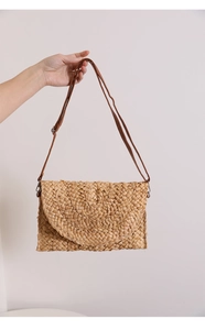 Detail of hand-woven straw shoulder bag showing natural textures and leather strap