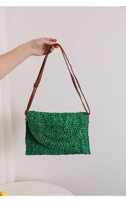 Detail of green straw woven crossbody bag with brown leather strap and texture