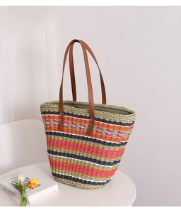 Detail of colorful striped straw tote bag with brown leather straps and metal rivets