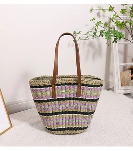 Detail of colorful striped straw tote bag with brown leather handles and a dark lining