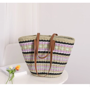 Close-up of woven straw tote bag featuring colorful stripes and premium brown leather handles