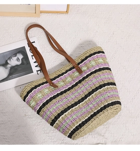 Close-up of a colorful striped woven straw tote bag with brown leather shoulder straps
