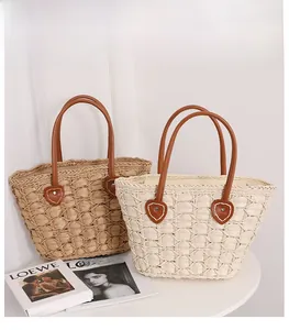 Detailed weave pattern and sturdy brown leather handles of this heart-shaped straw bag