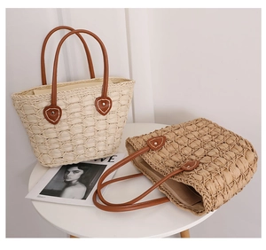 Detail of hand-woven straw tote with leather handles and heart-shaped stitched accents