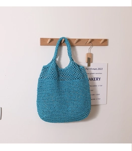 Close-up of blue straw woven tote bag featuring an intricate hollow out mesh pattern