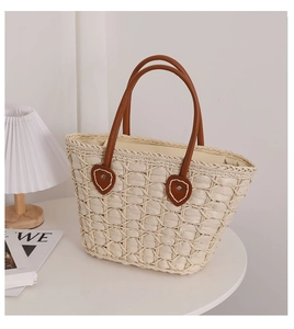 Close-up of heart leather patch with white stitching on straw tote with leather handle